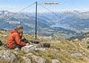 SOTA-activaties: techniek en veiligheid Radioamateur bedient een draagbaar SOTA-station met draadantenne en mast op een bergtop.